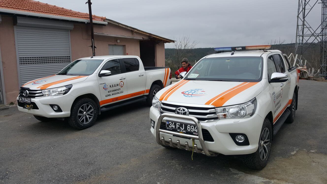Profesyonelce giydirilmiş beyaz pick-up, açık havada park halinde, şirket bilgileri net bir şekilde sergileniyor.